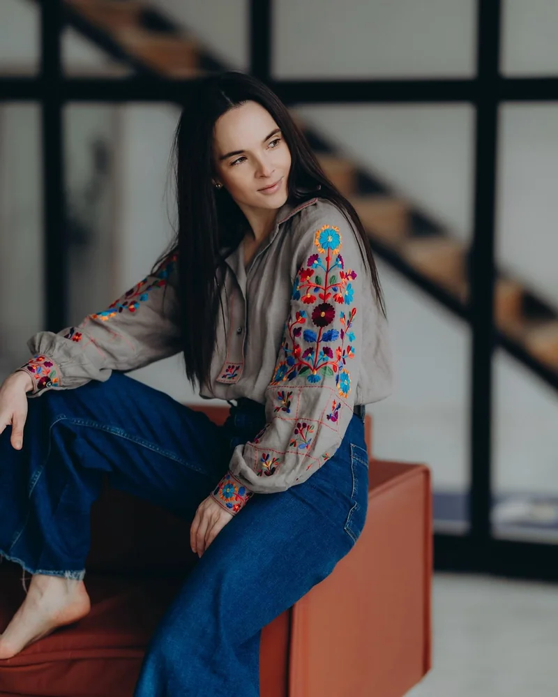 Woman in a vyshyvanka with colourful floral embroidery on the sleeves and wide-leg jeans