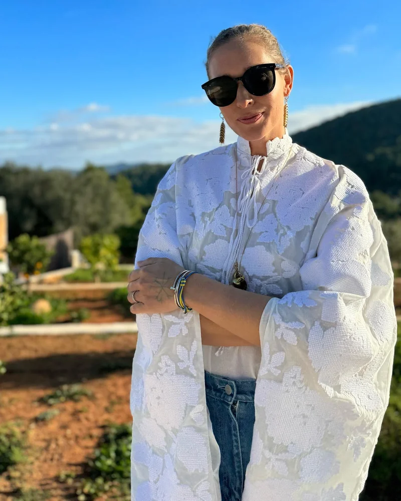 Woman in a white vyshyvanka with wide sleeves, jeans and sunglasses