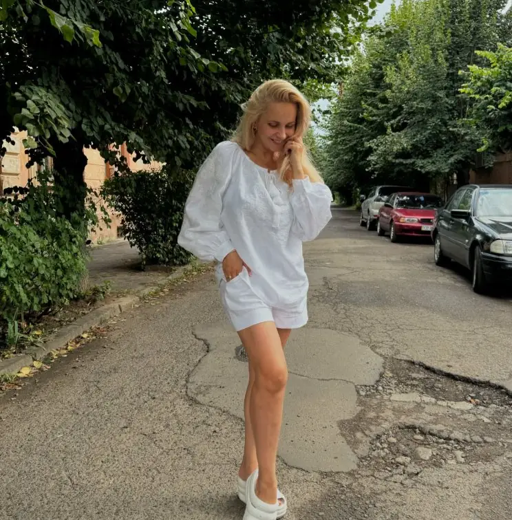 Woman in a white vyshyvanka and white shorts on a city street